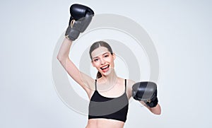 Happy young athletic girl in boxing gloves raised her hands up