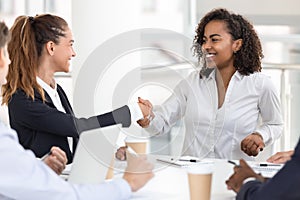 Happy young attractive black woman handshaking with white businesswoman