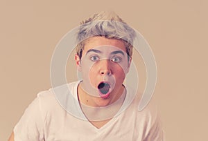 Happy young attractive teenager man shocked with surprised funny face. Human expressions
