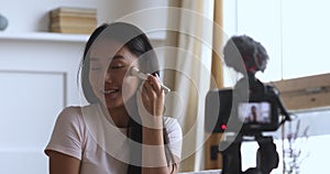 Happy young attractive vietnamese woman blogger recording video.