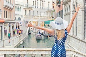 Happy young attractive woman of venice italy rising hands grand canal view blue polka dot outfit