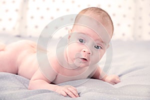 Happy young baby lying on tummy on a white background