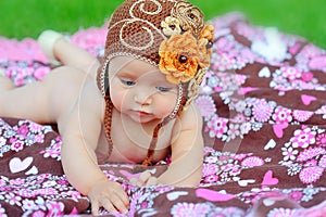 Happy young baby is sitting on green grass outside with bright