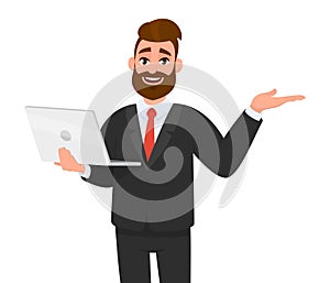 Happy young bearded business man holding/showing a latest new laptop and gesturing, showing, pointing or presenting something.