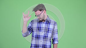 Happy young bearded hipster man with rock hand gesture