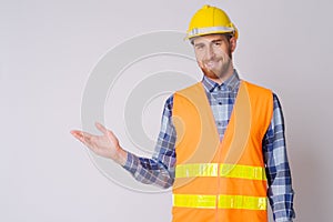 Happy young bearded man construction worker showing something