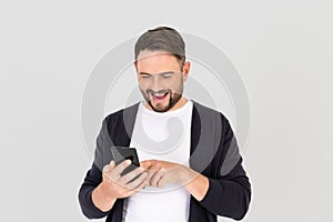 Happy young bearded man using mobile smart phone for mobile application online, social media, on gray background
