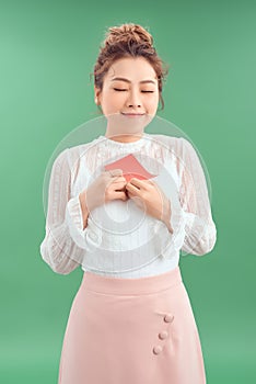 Happy young beautiful Asian girl with a love postcard valentines on green background