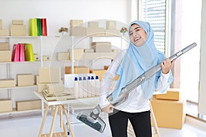 Happy young beautiful asian muslim housewife woman cleaning and playing vacuum cleaning like guitar with SME and E-commerce