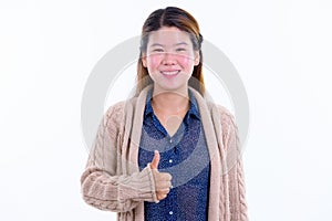 Happy young beautiful Asian woman giving thumbs up ready for winter