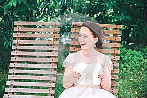 Happy Young beautiful bride with a cup of coffee waiting for her groom.Young beautiful bride drinking coffee at the outdoors cafe