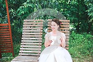 Happy Young beautiful bride with a cup of coffee waiting for her groom.Young beautiful bride drinking coffee at the outdoors cafe