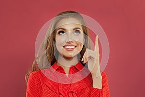 Happy young beautiful cheerful woman pointing up on colorful pink background portrait. Student girl pointing finger and looking up