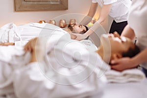 Happy young beautiful couple enjoying head massage at the spa