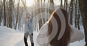 Happy young beautiful couple spend time in sunny winter forest together