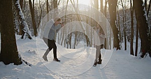 Happy young beautiful couple spend time in sunny winter forest together