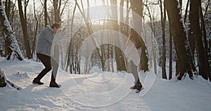 Happy young beautiful couple spend time in sunny winter forest together