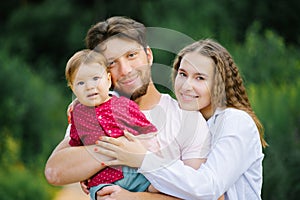 A happy young beautiful family with a young son is enjoying a wonderful day in the summer park