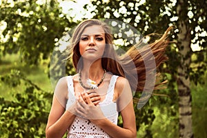 Happy young beautiful girl standing in the wind outdoor, holding