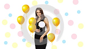 Happy young beautiful hostess woman holding greeting card surrounded by yellow air balloons