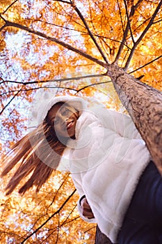 Happy young beautiful woman in autumn park on sunny day, Young woman in white coat during sunset in the park