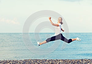 Happy young beautiful woman jumping at beach on the Sea