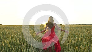 Happy young beautiful woman in red dress arms raised running on wheat field in sunset summer, Freedom health happiness