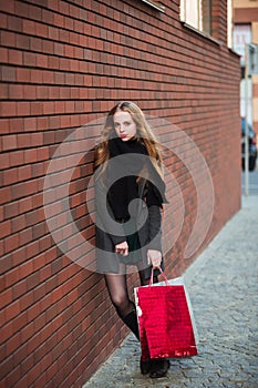 Happy young beautiful women holding shopping bags, walking away from shop on city street. Sale, consumerism and people