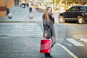 Happy young beautiful women holding shopping bags, walking away from shop on city street. Sale, consumerism and people