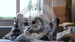 Happy young beauty couple in love having Pillow Fight on sofa couch, enjoying funny leisure activity together at home