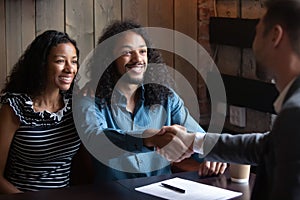 Happy young biracial couple clients and financial advisor shaking hands