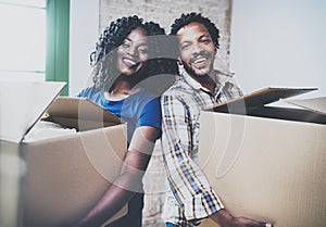 Happy young black african couple moving boxes into new house together and making a successful life.Cheerful family