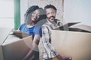 Happy young black african man and his girlfriend moving boxes into new house together and making a successful life