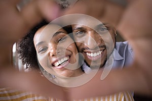 Happy young Black couple faces in finger heart shaped frame