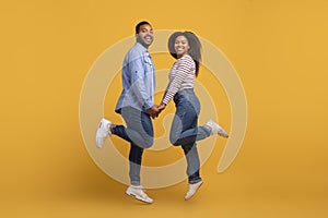 Happy young black couple holding hands and jumping in unison