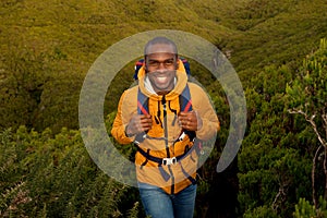 Happy young black man hiking in nature with backpack