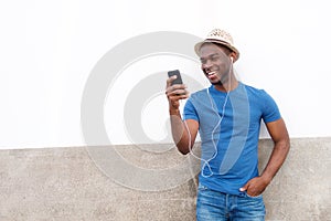 Happy young black man listening to music with mobile phone and earphones