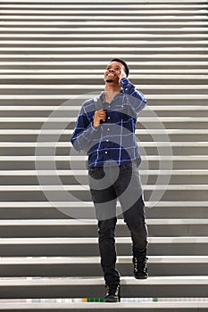 Happy young black man on stairs talking on mobile phone