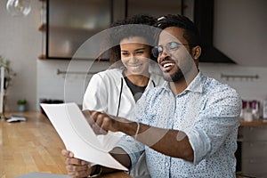 Happy young black married couple reading paper letter about reward