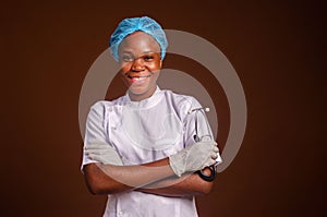 Happy young black nurse with crossed arms looking at a camera isolated on brown background.