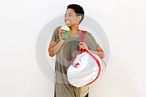 Happy young black woman with bag drinking fruit juice