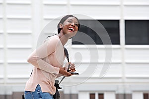 Happy young black woman with bag and mobile phone