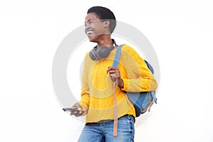 Happy young black woman with bag and mobile phone by white background