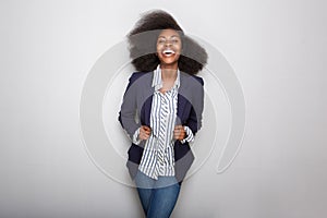 Happy young black woman with blazer against gray background