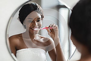 Young black woman with braces brushing her teeth