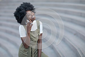 Happy young black woman calling by mobile phone outdoors in the city