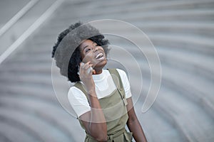 Happy young black woman calling by mobile phone outdoors in the city