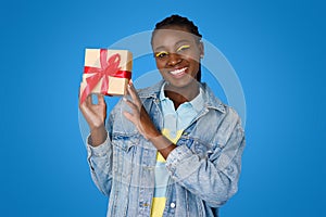 Happy young black woman celebrating birthday, showing her present