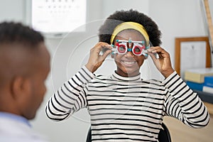 Happy Young black woman checking vision with eye test glasses during a medical examination at the ophthalmological office,