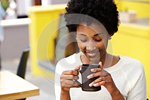 Happy young black woman drinking coffee